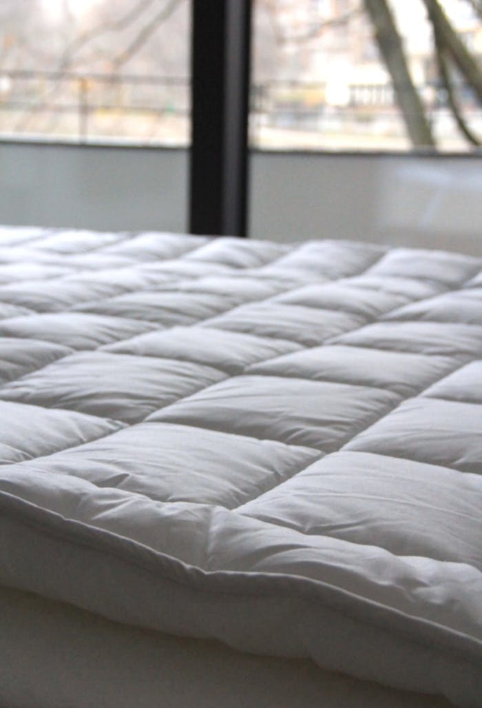 Close-up of a comfortable white quilted bedspread in a serene indoor setting.